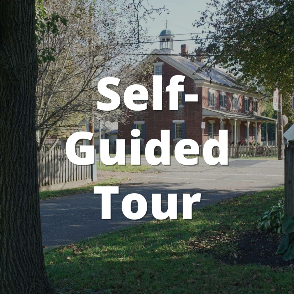 Image of a street in Historic Zoar Village with a historic building in the background and text overlayed on the image that says "Self-Guided Tour".